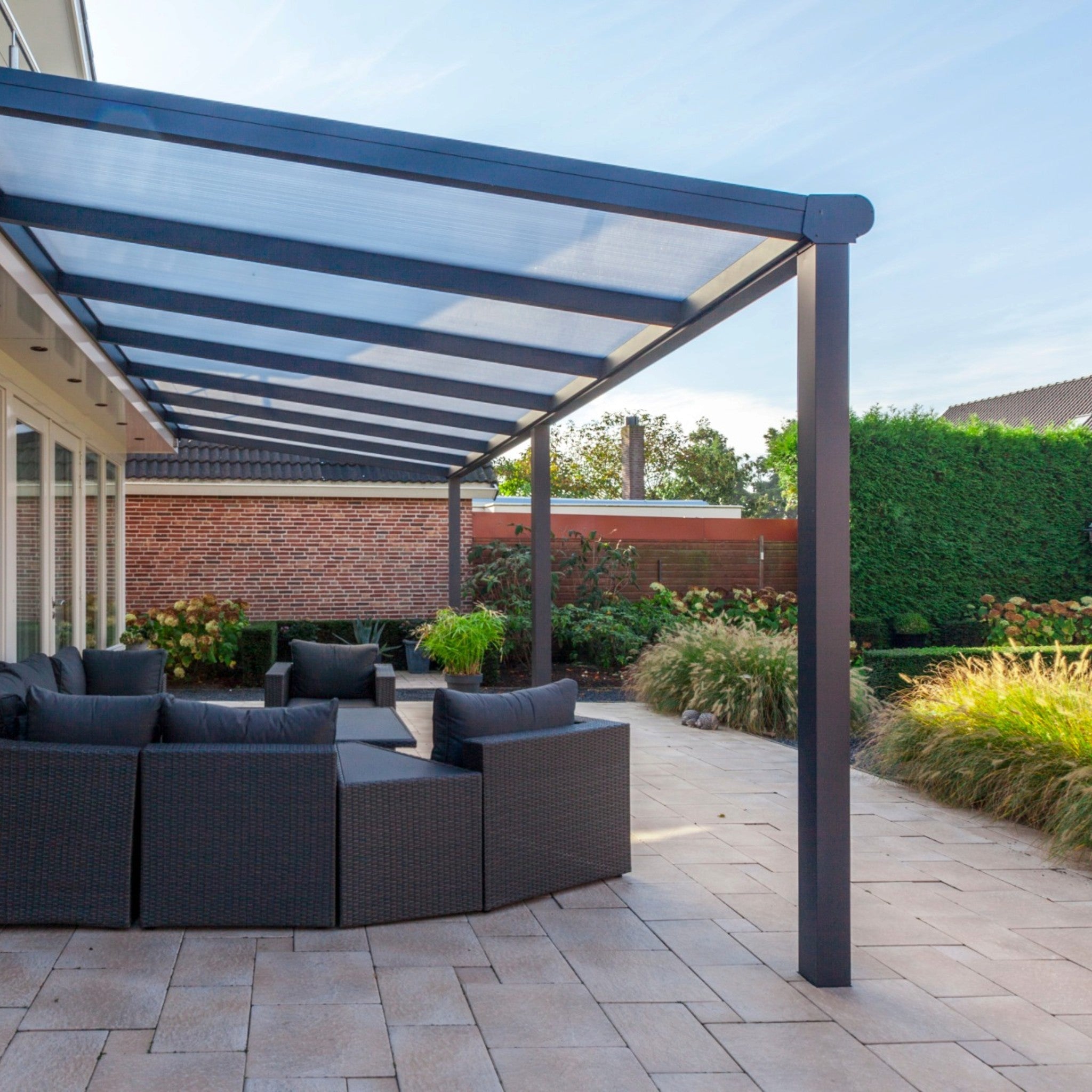 Deponti Bosco aluminium veranda in Anthracite Grey covering a patio with outdoor corner sofa